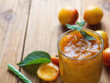 Tahta arka planda bir bardakta kayısı püresi.