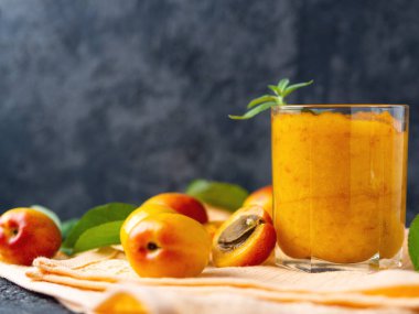 Tahta arka planda bir bardakta kayısı püresi.