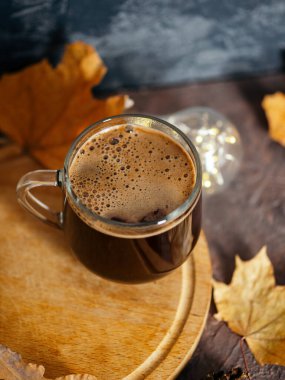 Arka planda sonbahar kuru yaprakları olan cam espresso kahve fincanı. Sıcak kahveyle soğuk mevsim