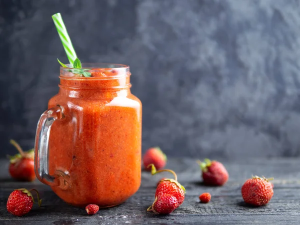 Strawberry red summer smoothie in a jar with copyspace. Ripe berries and a very healthy smoothie
