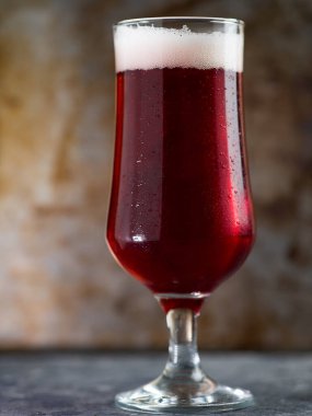 Paslı metal bir arka planda bardakta kırmızı bira.