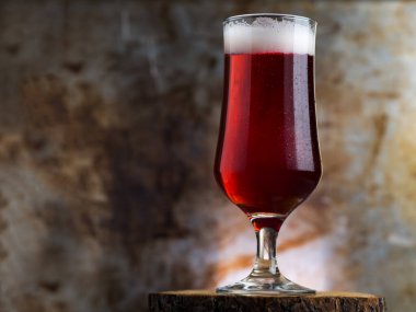 Koyu metal arka planda bir bardak kırmızı bira.
