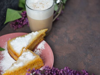 Kahve ve havuçlu kek beton bir arka planda leylak çiçekleriyle