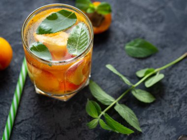 Summer apricot drink cocktail with pieces of fruit and mint