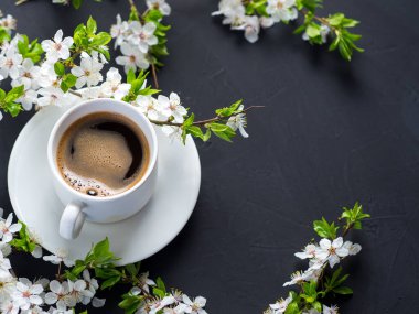 Taş bir masada beyaz bir fincan espresso kahve, beyaz kiraz çiçekleri, ilkbahar fotokopi alanı.