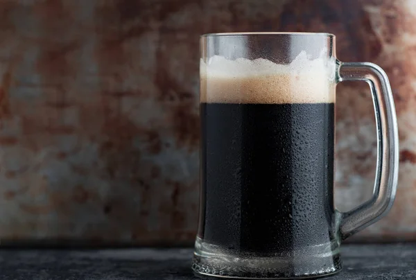 Glass mug pint of dark beer on an iron background