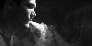 Genç erkek banyocuların portresi. Elektronik sigaradan buhar çıkarıyor.