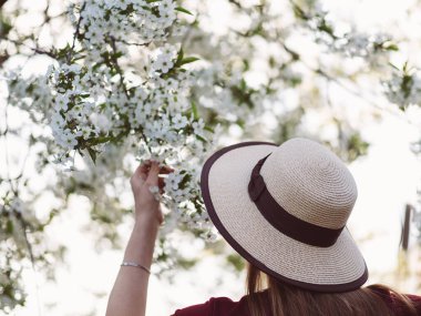 Baharda çiçek açan bahçede şapkalı bir kadın
