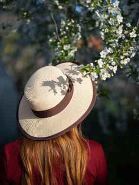 Baharda çiçek açan bahçede şapkalı bir kadın