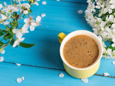 Bahar kahvesi. Mavi arka planda sarı kupa ve kiraz çiçekleri