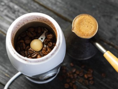 Ahşap arka planda kahve öğütücüsü ve demlikte taze kahve.