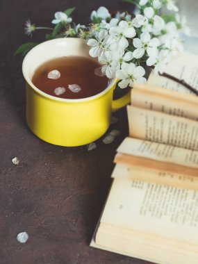 Bahar çayı ve masada kiraz çiçekleri olan eski bir kitap.