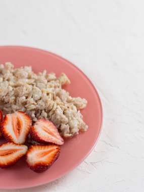 Beyaz bir masada çilekli yulaf ezmesi. Sağlıklı ve lezzetli kahvaltı.