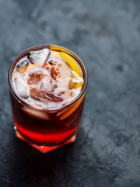 Koyu taş masada portakallı Negroni kokteyli.