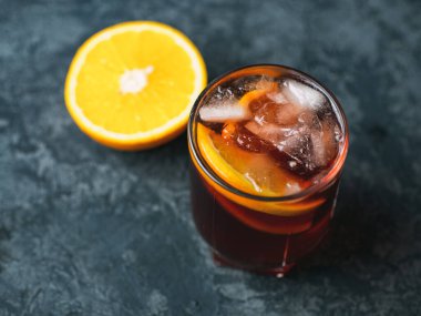 Koyu taş masada portakallı Negroni kokteyli.