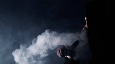 Tencere adam. Siyah şapkalı yakışıklı bir adamın portresi ve siyah arka planda sigara buharı püskürten ve nefes veren bir gözlük.