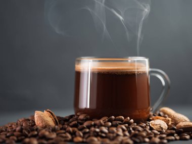 Beton bir masada rendelenmiş bademle birlikte bir bardak kahve ve dağınık kavrulmuş tahıllar.