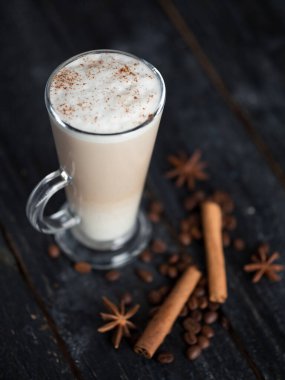 Koyu ahşap bir masada tarçınlı ve anasonlu büyük bir bardak kahve.