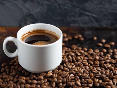 Kızarmış kahve çekirdekleri üzerine beyaz bir fincan espresso.