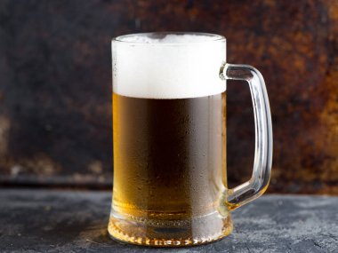 Paslı arka planda su damlaları olan bir bardak light bira.