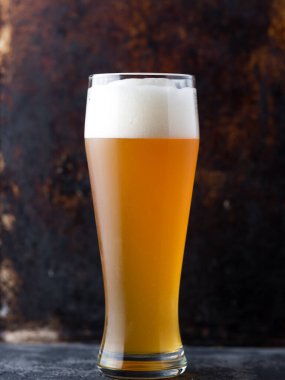 Yakın plan - koyu kahverengi arka planda geleneksel filtresiz buğday birası bardağı