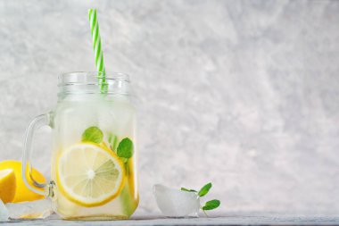 Buzlu ferahlatıcı ev yapımı limonata. Gri masa fotokopisinde limon ve naneli.