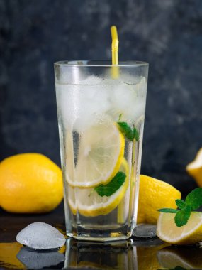 Limonlu, naneli, buzlu, koyu beton bir masada bir bardak yaz limonatası