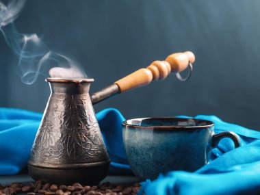 Bir fincan aromatik kahve, kavrulmuş kahve çekirdeği. Güzel mavi kupa ve jezva