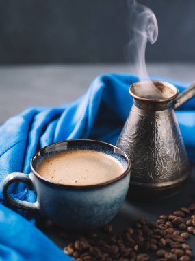 Bir fincan aromatik kahve, kavrulmuş kahve çekirdeği. Güzel mavi kupa ve jezva