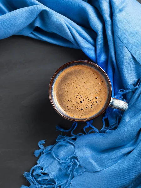 Top view of a blue coffee cup standing on a dark table, copy space