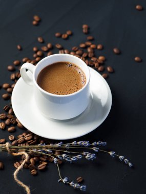 Beton bir masada kavrulmuş tahıllar ve kuru yapraklarla bir fincan espresso.