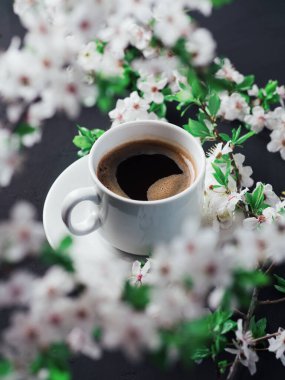 Kiraz çiçekli beyaz bir fincan espresso kahvesi. bahar zamanı kompozisyonu