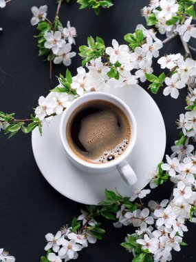 Bir fincan mis kokulu kahve ve çiçek açan kiraz ağaçları.