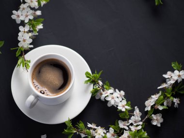 Bahar kiraz çiçeklerinin dallarıyla beton bir masanın üzerinde bir fincan kahve ve kopyalama alanı.