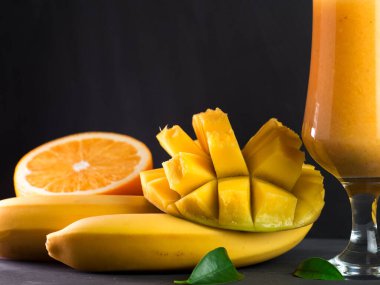Lezzetli ve sağlıklı egzotik smoothie. Siyah arka planda portakal ve muz.
