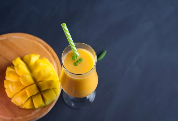 Yüksek bardakta mangolu smoothie kokteyli. Egzotik, sağlıklı kahvaltı, fotokopi alanı, karanlık masa