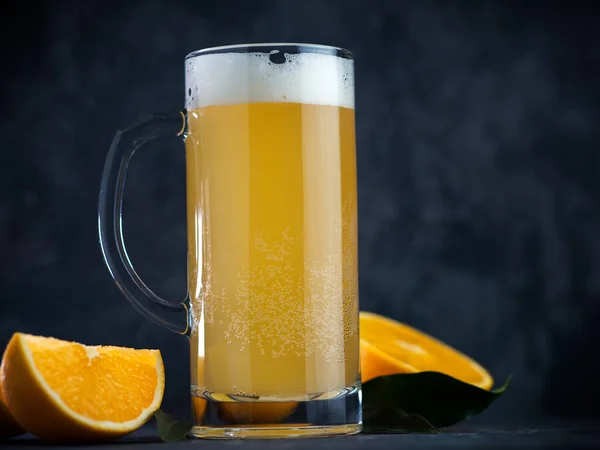 Fruit juicy summer beer in a glass mug with orange . Radler beer