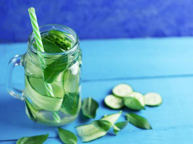 Salatalık doldurulmuş su, ahşap mavi zemin üzerinde nane ve kopyasal alan.