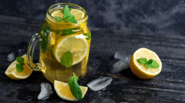 Cam kavanoz soğuk limonata ya da limonlu mojito, nane, çay ve buz koyu ahşap bir masada.