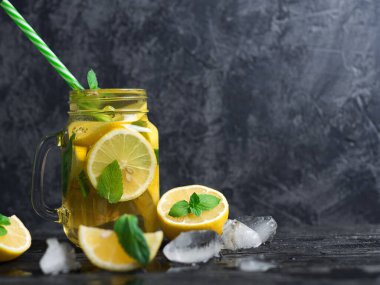 Cam kavanoz soğuk limonata ya da limonlu mojito, nane, çay ve buz koyu ahşap bir masada.