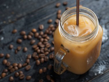 Koyu bir masada pipetli, cam bir kavanoz soğuk kahve.