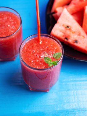 Faydalı bir yaz. Mavi arka planda gözlüklü ferahlatıcı karpuz smoothie.