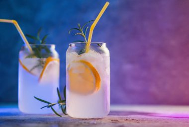 İki bardak buzlu limonata ve bir tutam biberiye. Cin ve alkollü kokteyl. Neon tarzı arkaplan, yaratıcı moda gözlükleri, kopyalama alanı