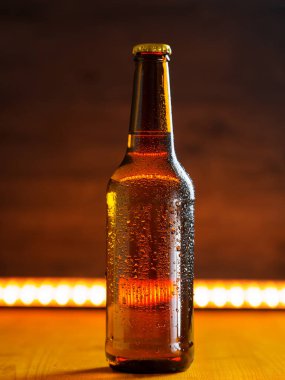 Su içinde soğuk bir bira şişesi masanın üstüne ışık tutuyor.