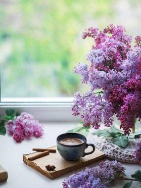 Bahar geldi. Pencere kenarında seramik bir fincan espresso, bir buket leylak çiçeği, eski bir kitap.