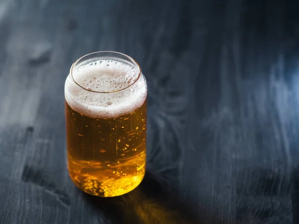 Creative Fashion Beer Glass in the shape of a can. Light beer lager on a dark table