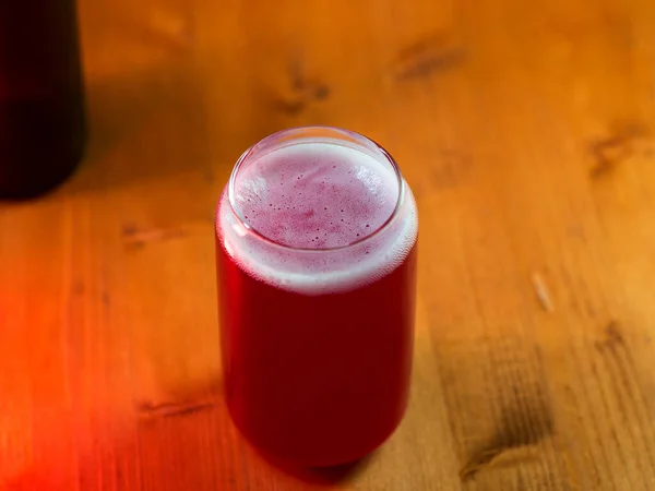 Summer red fruit craft beer sour ale. Stylish glass in the form of a can of beer. Wooden table