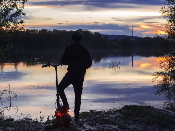 Unga Manliga Ryttare Elektrisk Skoter Flodstranden Vid Solnedgången Bakifrån Färgglada — Stockfoto