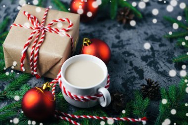 Sıcak sabah kahvesi ve Noel hediyesi masanın üzerinde ağaç dallarıyla.