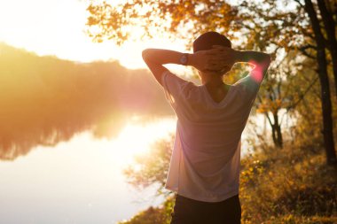 Bir adam ekim ayında batan güneşin tadını çıkarır. Sıcak ve güzel bir sonbahar.